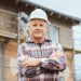 Proud plasterer standing in front of scaffold on construction site crossing arms